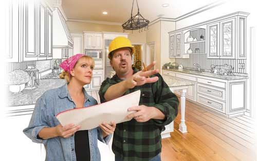 A contractor with a hard hat on discussing the blueprints with a woman on a new house